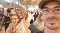 Familie mit einem Mann im Vordergrund, einer Frau und einem Kind auf ihrem Rücken in einer belebten, modernen Bahnhofshalle