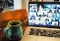 Grüne Keramiktasse auf Holztisch neben offenem Laptop mit Videokonferenz und mehreren Teilnehmern auf dem Bildschirm