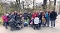 Gruppe von Erwachsenen und Kindern mit Kinderwagen auf einem Weg im Park bei bewölktem Himmel