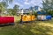 Spielplatz mit buntem Holzzug auf Rasenfläche vor mehrstöckigem Gebäude und Bäumen