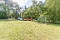 Spielplatz mit kleinem Fußballtor, Fußball auf Grasfläche und buntem Spielzug aus mehreren Waggons vor Waldkulisse