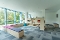 Kinderspielzimmer mit großen Fenstern, Sitzbank mit bunten Polstern und Regalen mit Spielzeug und Büchern