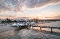 Strand mit Seebrücke und Gebäuden im Hintergrund bei Sonnenaufgang mit bewölktem Himmel