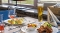 Teller mit paniertem Schnitzel, Zitronenscheibe und Petersilie, daneben Schüssel mit gemischtem Salat, im Hintergrund Weinglas mit Rosé und Glas mit Bier auf einem Tisch.