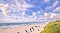 Strand mit Sand, Dünen und mehreren Menschen, die am Wasser und auf dem Strand spazieren