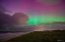 Nordlicht am Himmel über einer Küstenlandschaft mit Strand und Dünen bei Nacht