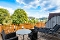 Balkon mit rundem Tisch, vier Stühlen aus Korbgeflecht und zwei Liegestühlen mit Blick ins Lahntal.