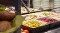 Buffet mit verschiedenen Salaten und Gemüse in rechteckigen Schalen hinter einer Glasabdeckung