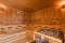 Innenraum einer Sauna mit Holzbänken, Holzwänden und einem Saunaofen mit Steinen
