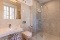 Modernes Badezimmer mit Waschbecken, Wandtoilette, Glasdusche und großem Spiegel